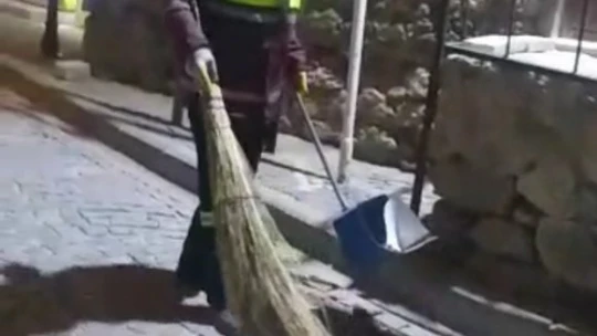 Hem çevreyi temizliyor hem de sokak kedisine süpürgesi ile masaj yapıyor